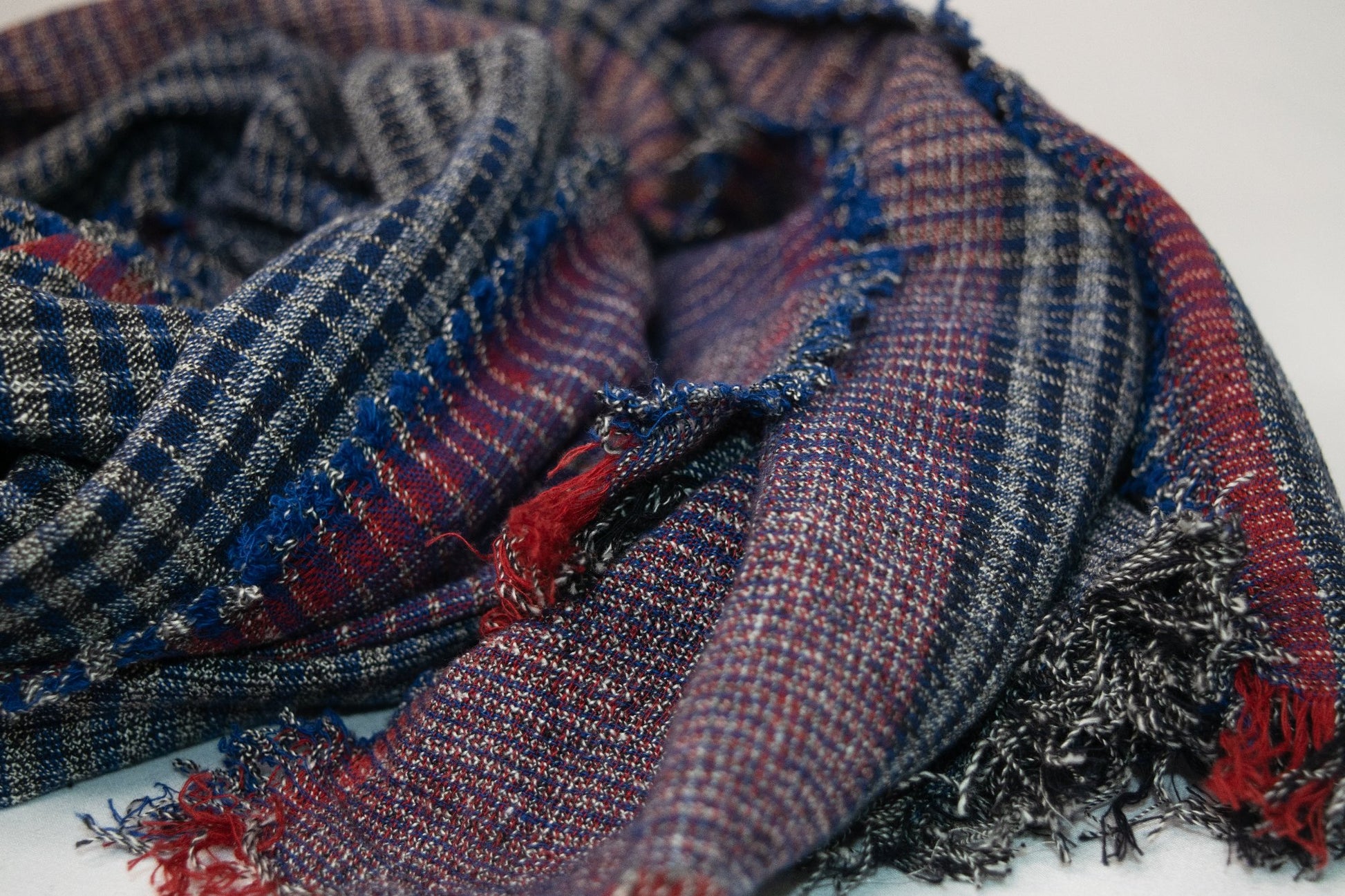 Black and blue plaid cotton scarf with red accents laid flat